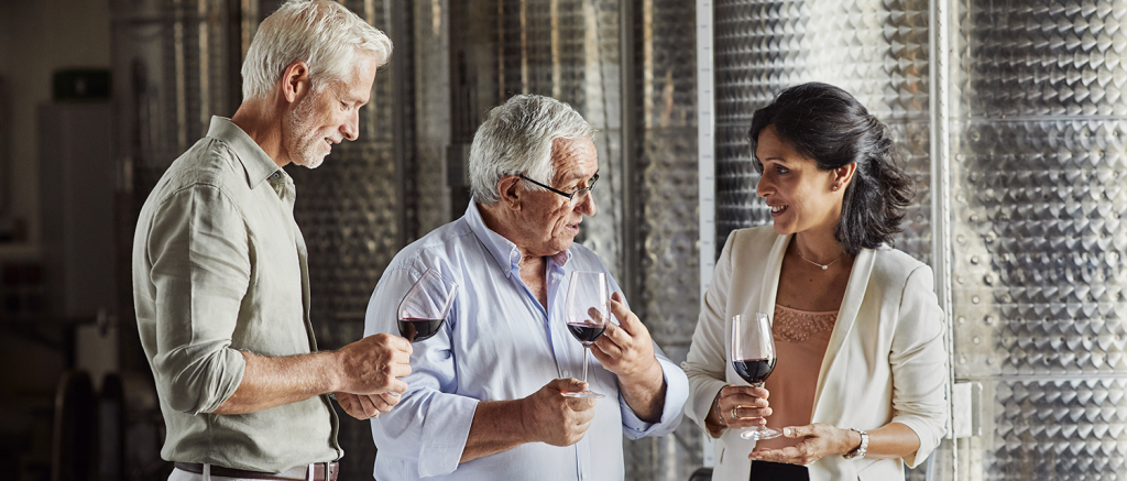 Trois personnes discutent et dégustent un verre de vin rouge au milieu de l'atelier VINIV.